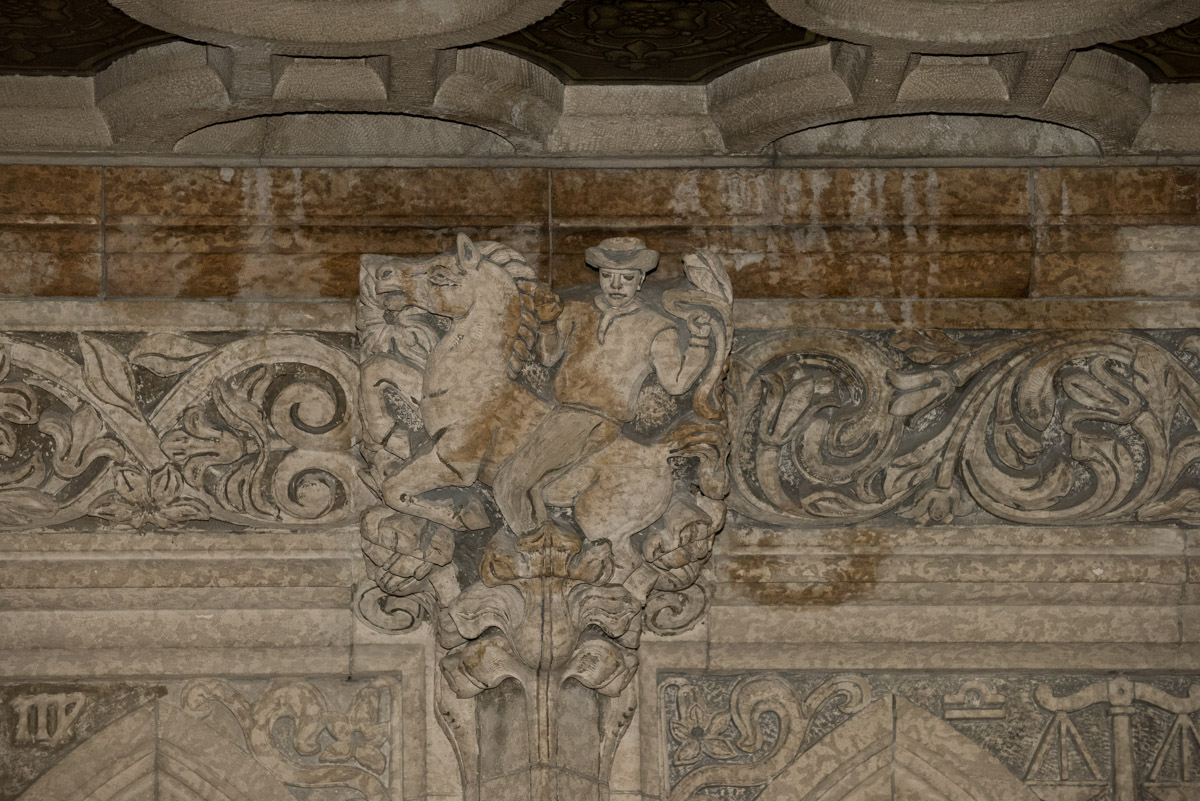 Enlarged image of rust-coloured stains cover a stone carving of a man on a horse