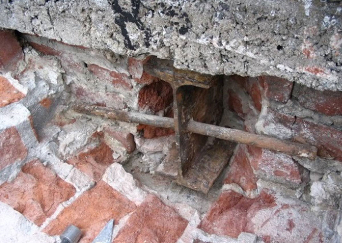 A steel beam inside a masonry wall. The beam is rusted and corroded.
