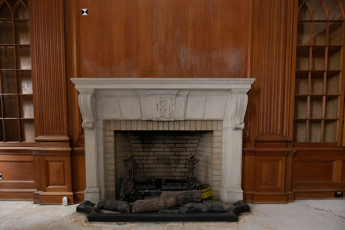 A fireplace with a carved stone mantelpiece.