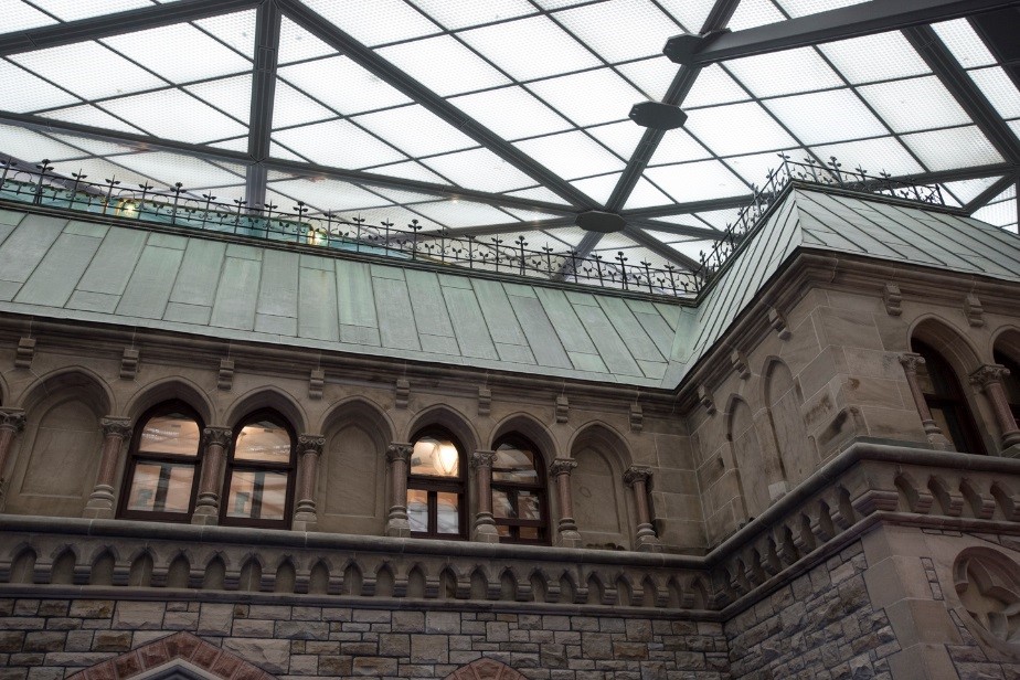 View enlarged image of the façade of a heritage stone building with a green copper roof. Above the façade is a glass roof.