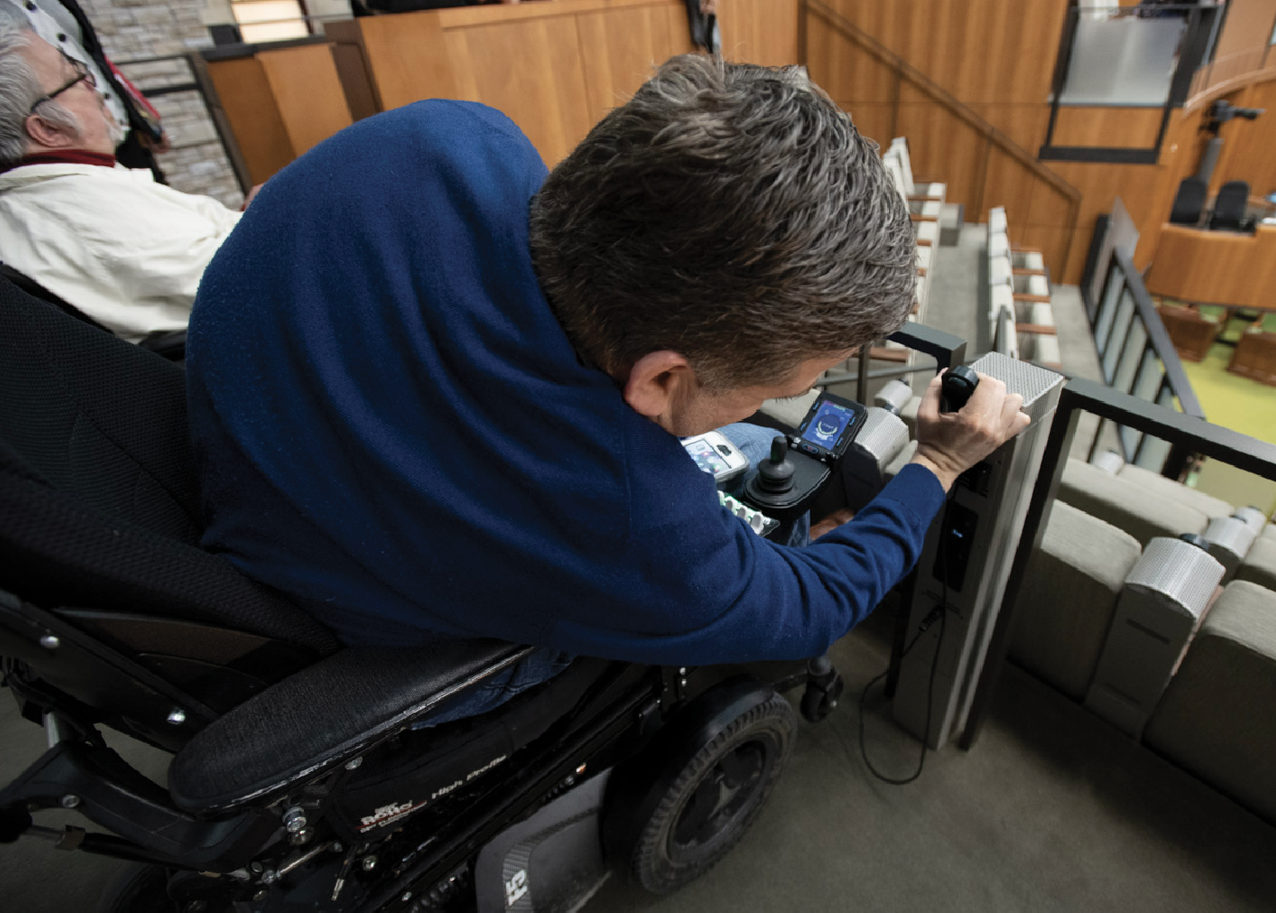 A person in a wheelchair in the gallery of the West Block Chamber.