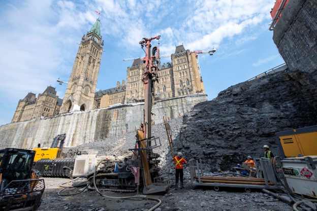 Des ouvriers utilisent une foreuse dans la fosse devant l'édifice du Centre