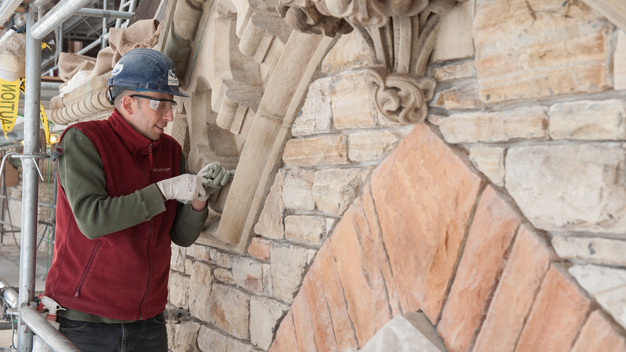 View enlarged image of a worker using a tool on a masonry stone wall.