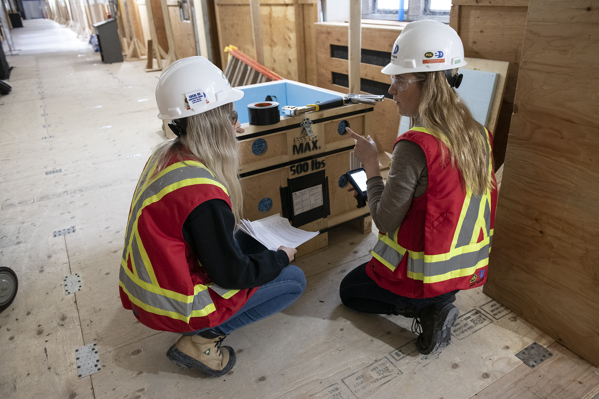 Two workers scan a wooden crate with a handheld device.