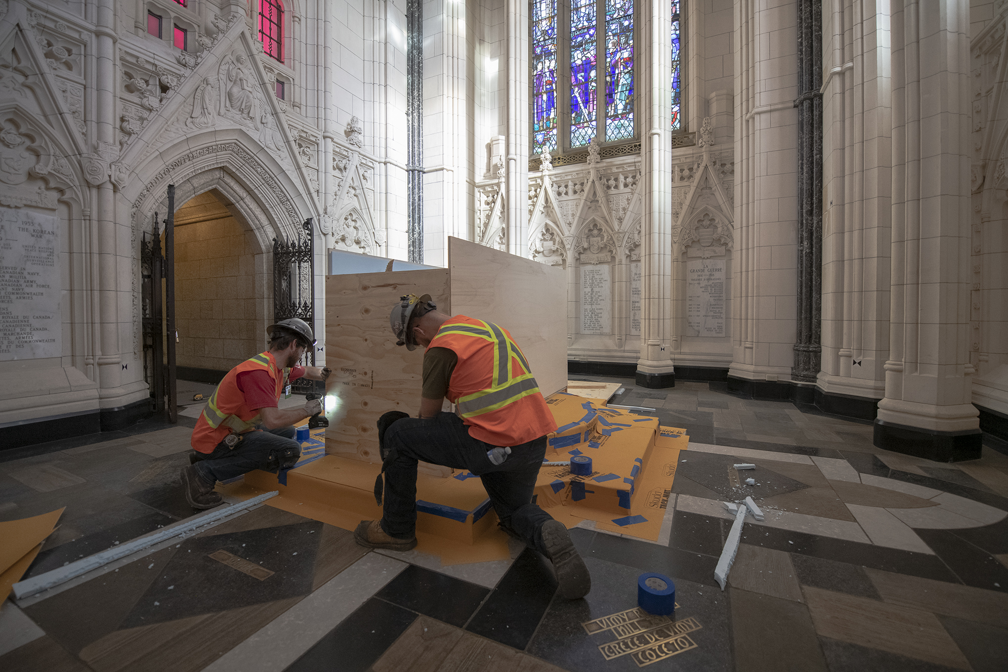 Two workers install plywood around a stone altar.