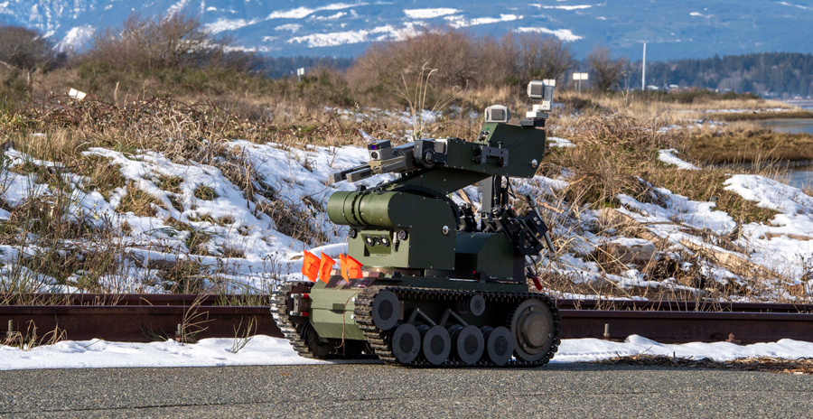 Explosive ordnance disposal robot on a snowy roadside with mountains in the background