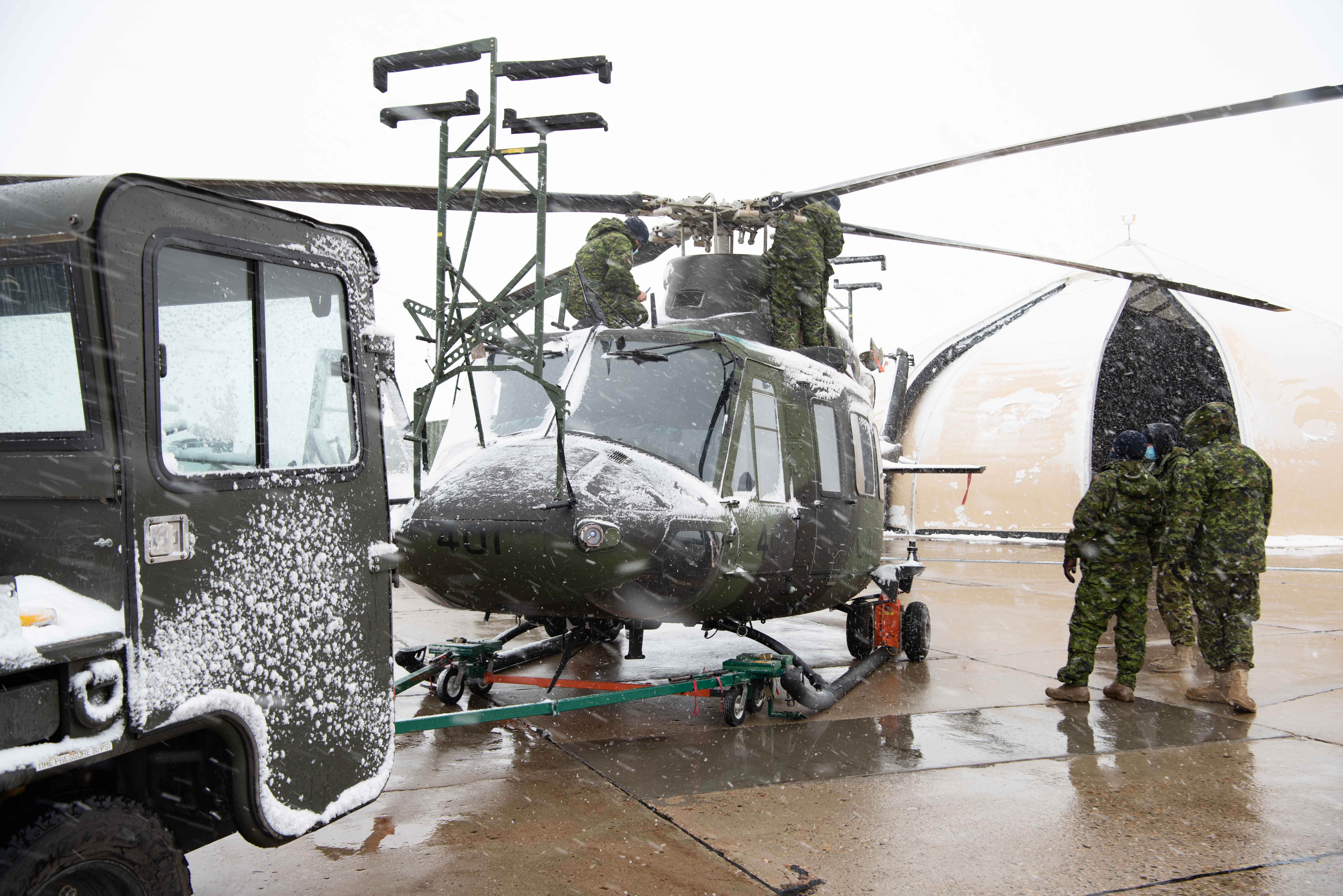 Aircraft technicians from 438 Tactical Helicopter Squadron perform maintenance on a CH-146 Griffon in the snow on May 20, 2021, at CFB Suffield. PHOTO: Cpl Laura Landry
