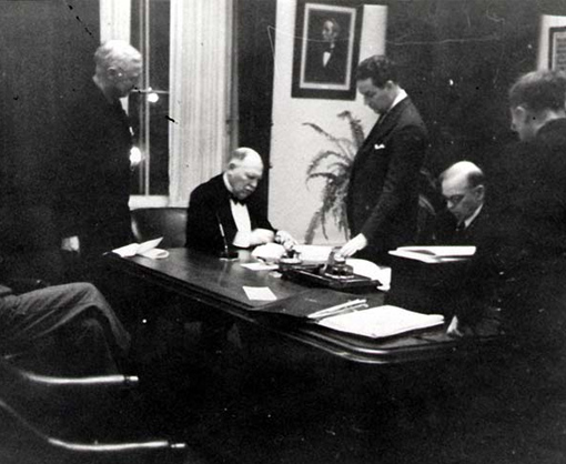 Lord Riverdale (seated, left) and Prime Minister William Lyon Mackenzie King (seated, right) sign the British Commonwealth Air Training Plan Agreement on December 17, 1939. PHOTO: DND Archives