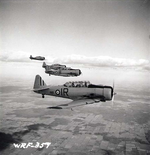 Four North American Harvards fly in formation near No. 2 Service Flying Training School at RCAF Uplands, Ontario, in July 1941. PHOTO: Nicholas Morant, PA-140659