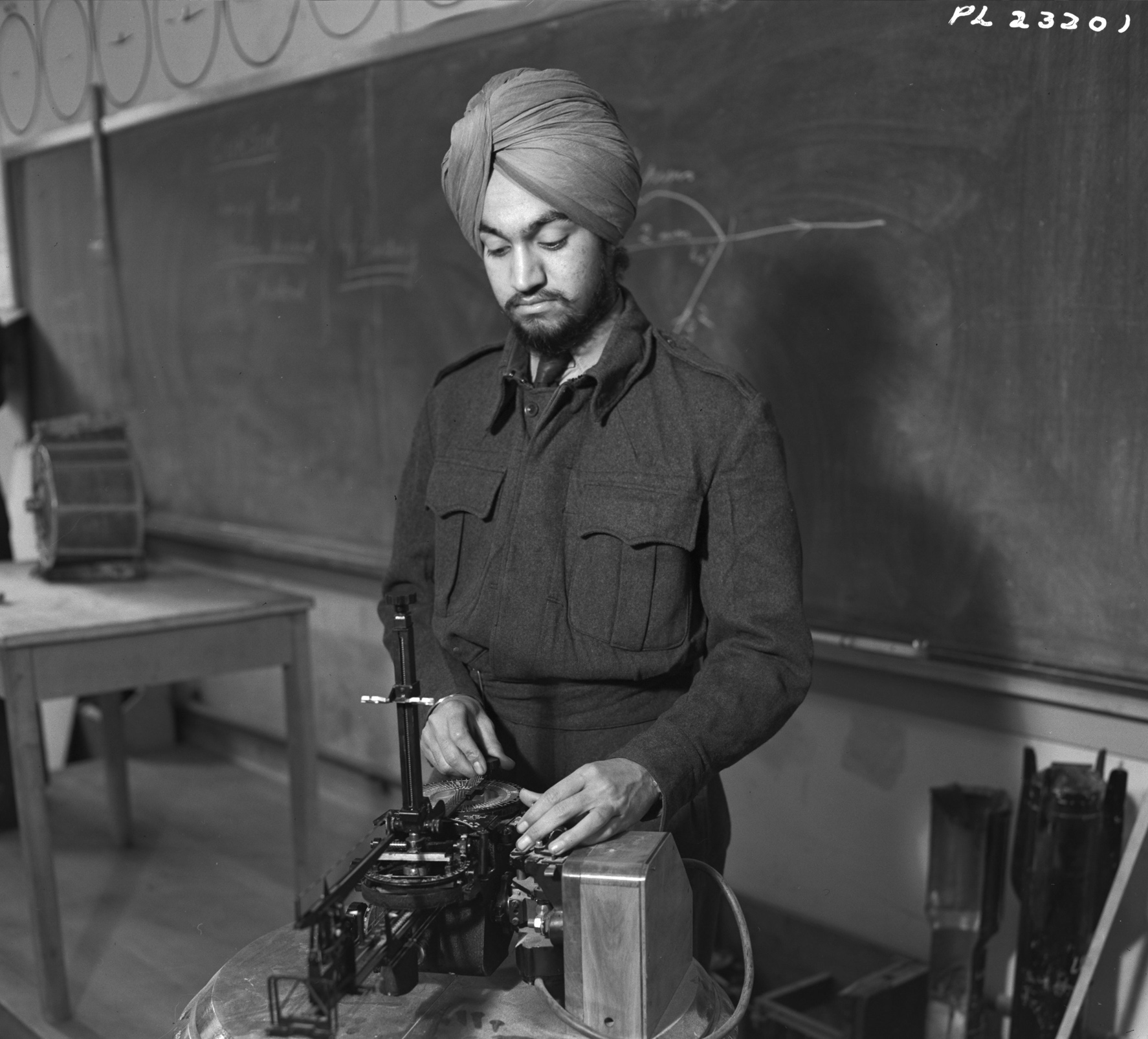 Leading Aircraftman Rajinder Singh Sandhu, from Pakho Pur, India, examines the mechanics of a bomb sight at No. 41 Service Flying Training School at RCAF Weyburn, Saskatchewan. PHOTO: DND Archives, PL-23201