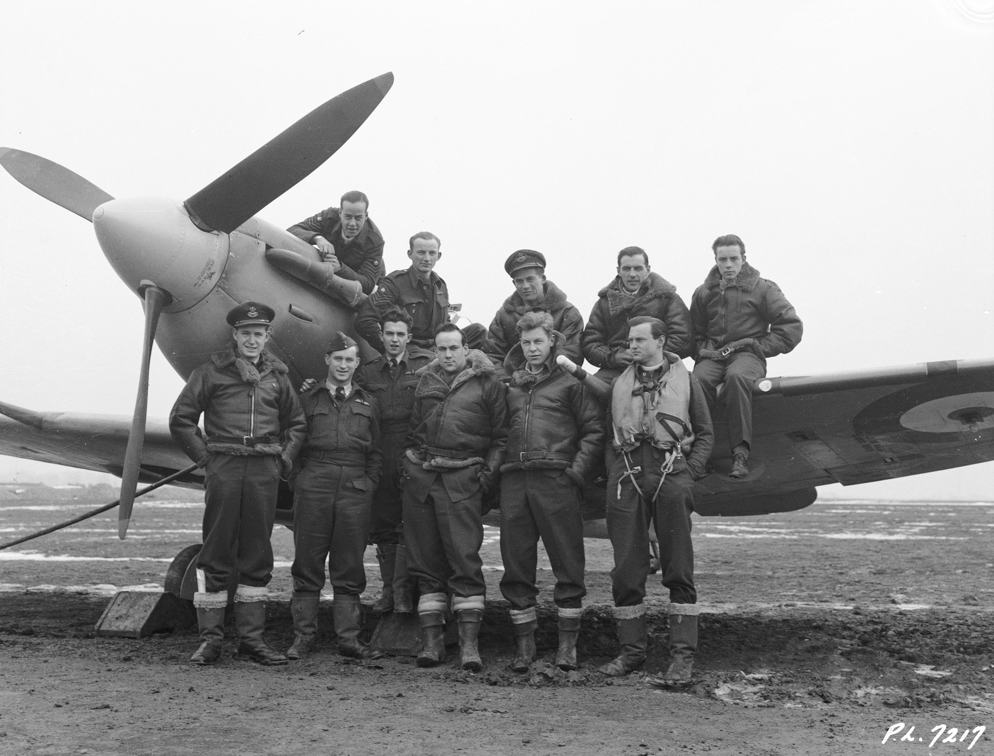 In RCAF squadrons based in Great Britain, most Spitfire aircrew were products of the British Commonwealth Air Training Plan in Canada. This photo, taken February 12, 1942, shows eleven members of 403 Squadron. Front, left: Pilot Officer J.N. Cawsey, Calgary, Alberta; Pilot Officer J.T. Parr, Barrie, Ontario; Flight Sergeant E.A. Crist, Wallaceburg, Ontario; Sergeant D.D. Connell, Hamilton, Ontario; Sergeant J.H. Oliver, Toronto, Ontario; and Sergeant H.R. Olmsted, Ottawa, Ontario. Back, left: Flight Sergeant J.B. Rainville, St. Johns, Quebec; Flight Sergeant A.H. McDonald, Fleming, Saskatchewan; Pilot Officer D.S. Hurst, Winnipeg, Manitoba; Flight Sergeant F.H. Belcher, Roblin, Manitoba; and Flight Sergeant G.A.J. Ryckman, London, Ontario. PHOTO: DND Archives, 