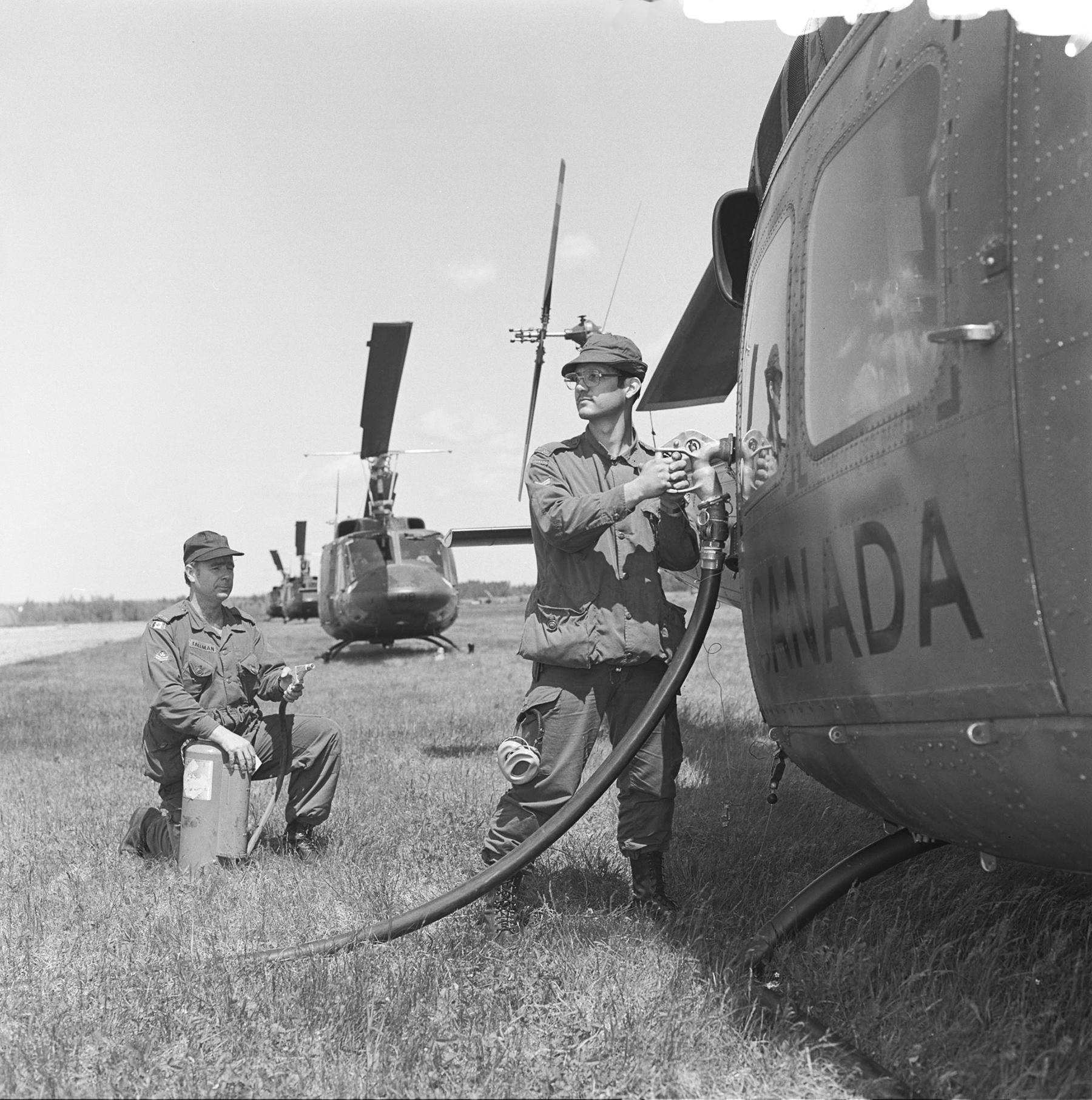 During Exercise Rendez-Vous 81, Corporal John Leroux refuels a 450 squadron CH-135 Twin Huey helicopter while another airman stands fire sentry. PHOTO: IM81-250, DND Archives