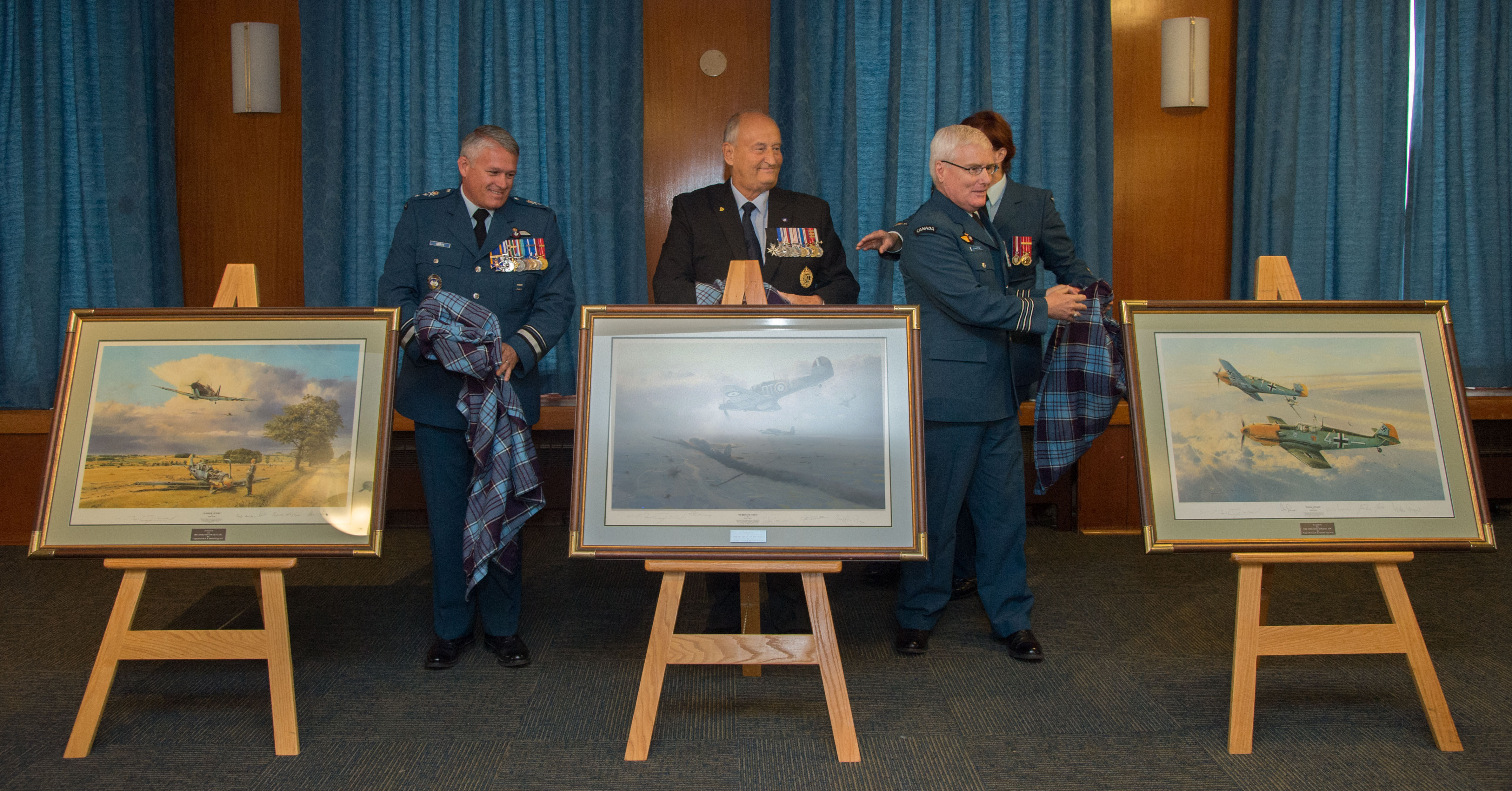 Three men reveal three paintings of aircraft.  