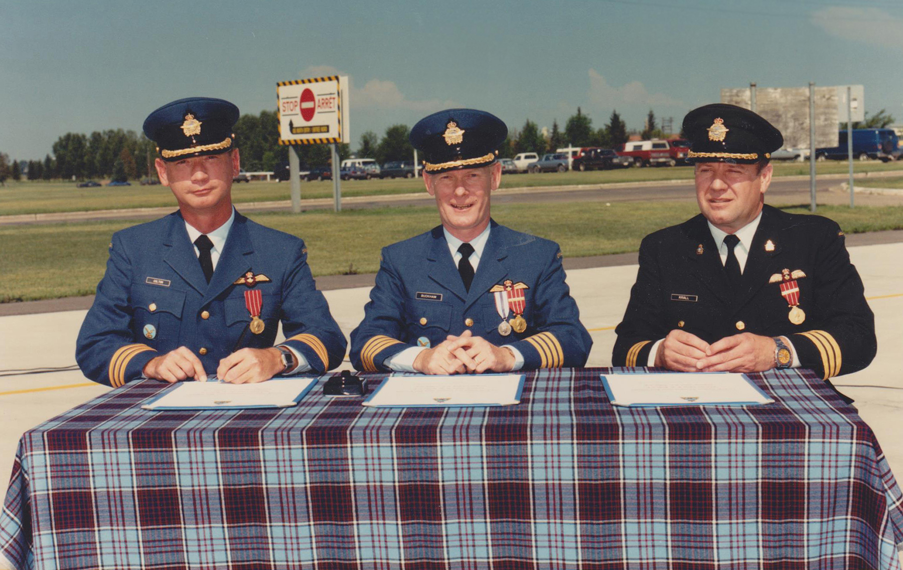 Atop the traditional drape of Royal Canadian Air Force tartan, Lieutenant-Colonel Chris Colton (left), incoming commanding officer of 440 Transport Squadron, and Lieutenant-Colonel Barry Krall (right), outgoing commanding officer of the squadron, flank Colonel Bill Buckham, 18 Wing Edmonton commander, during the squadron’s 1987 change of command ceremony. Lieutenant-Colonel Krall wears the recently phased out tri-service uniform, while the others wear the new. PHOTO: DND
