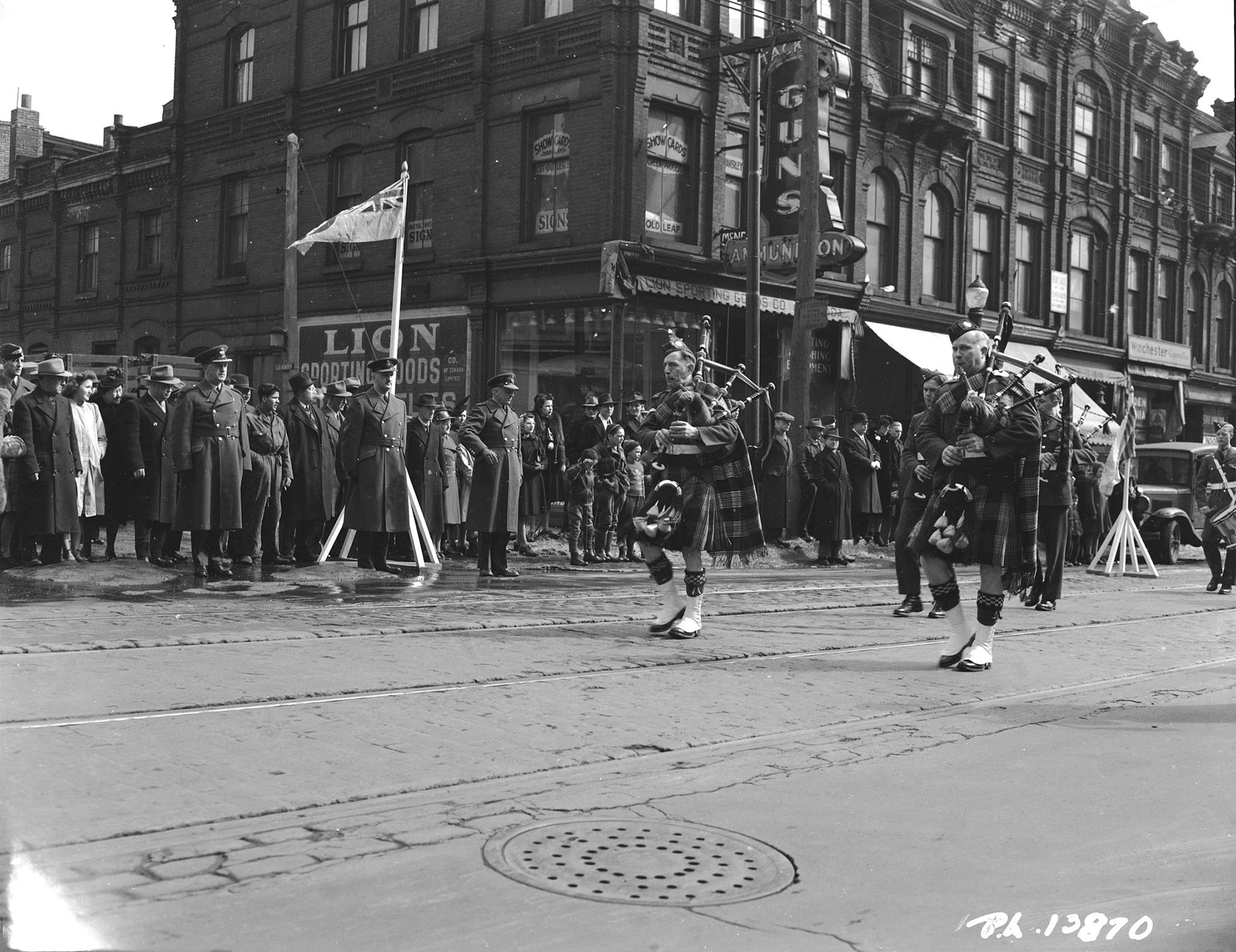 In full RCAF tartan regalia, the No. 9 Service Flying Training School Pipe Band from Centralia, Ontario, parades past Air Commodore G.E. Wait as he takes the salute on March 13, 1943, in Toronto, Ontario. The band was leading Royal Canadian Air Force airmen from Toronto`s No. 1 Manning Depot to Maple Leaf Gardens for a hockey playoff game between the Air Force and a team representing the Royal Canadian Navy. PHOTO: DND Archives, PL-13870
