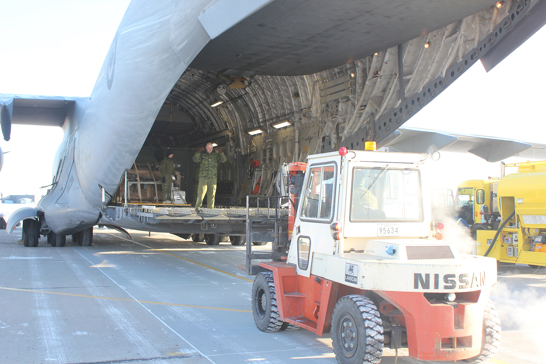 A front-end loader positions itself behind the open cargo ramp of a large aircraft.