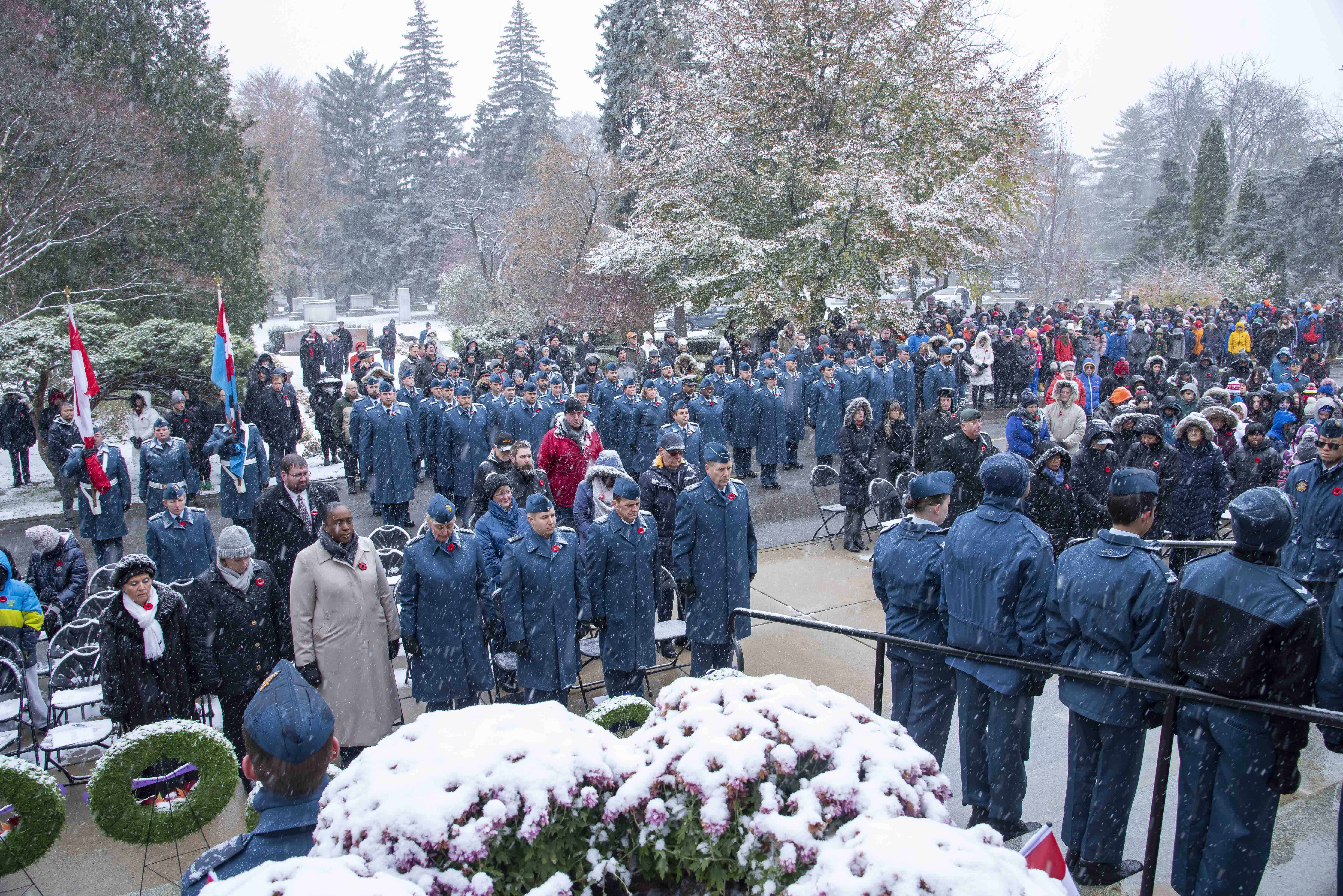 A large crowd of military personnel, veterans, youth and other members of the public stands in the falling snow during the 2019 Remembrance Day ceremony held at the mausoleum where Wing Commander William Barker, VC, is interred in Mount Pleasant Cemetery, Toronto. PHOTO: Corporal Lynette Ai Dang, BM10-2019-0359-026