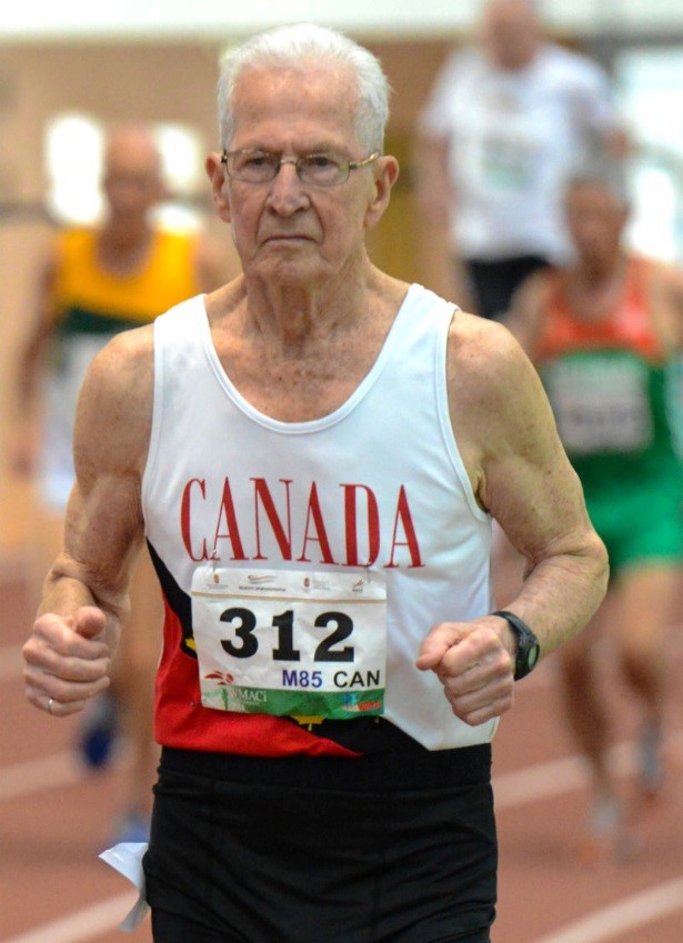 A senior man wearing Canada bib 312 runs on a track.