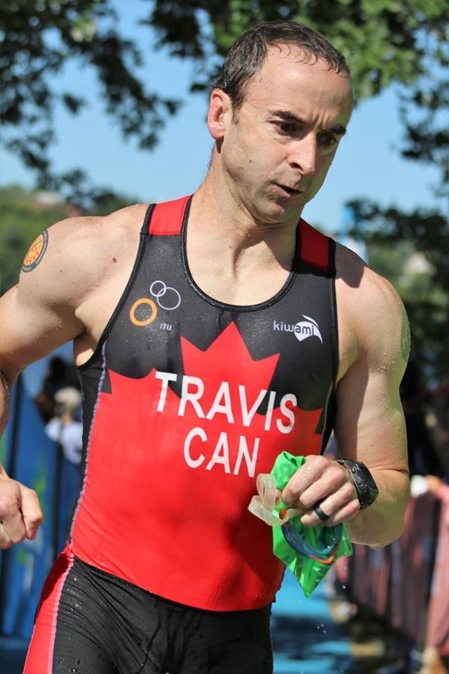 A man wearing a black and red sleeveless shirt participates in a triathlon.