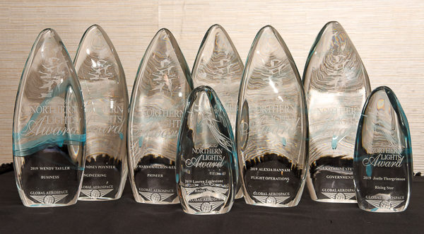 Huit trophées de verre sur une table.