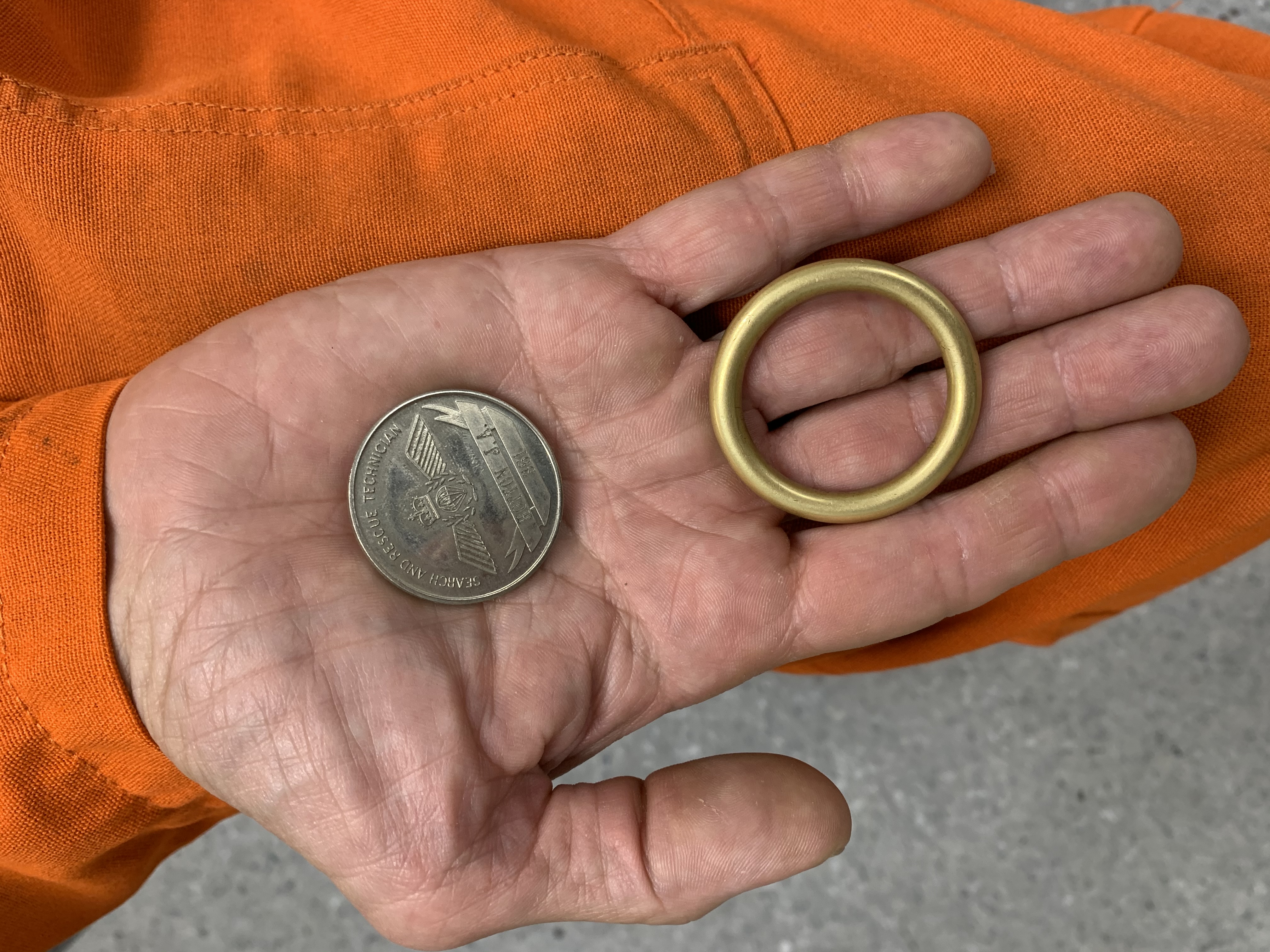 Two pocket finds: Sergeant André Hotton carries both his 1990 search and rescue training course #27 coin, and a well-worried brass ring from an old diving bag. PHOTO: Sara White