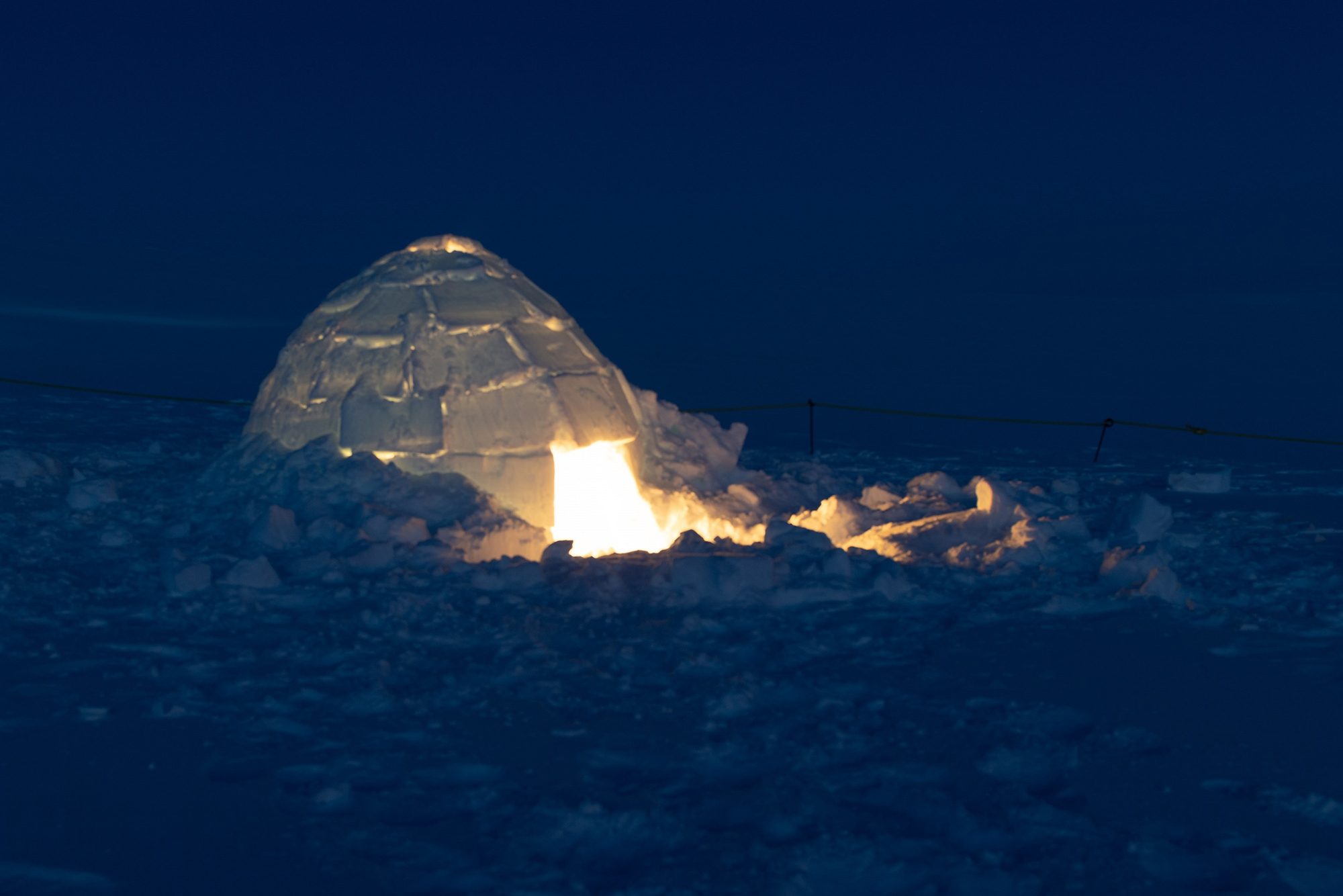 A photo of an illuminated igloo at night.