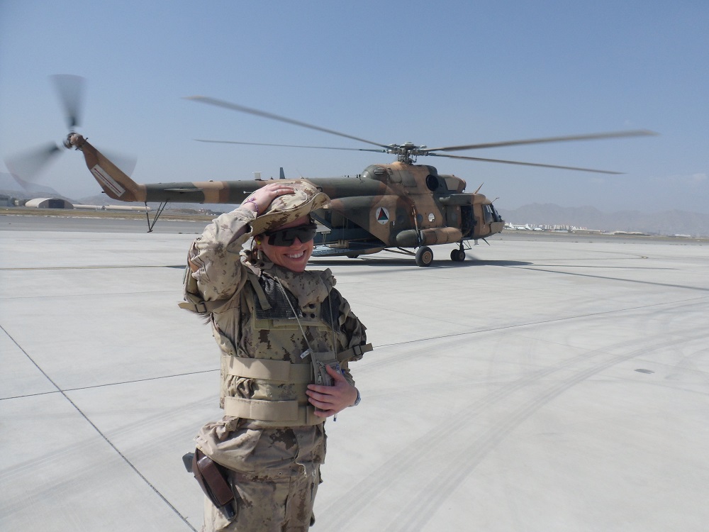 A military woman in front of helicopter