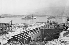 L’explosion d’Halifax du 6 décembre 1917 dévasta le port, mais, incroyablement, le Niobe échappa à la destruction et on le voit ici, sur la droite, surmonté d’un panache de fumée.