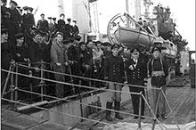 St. John’s : le Contre-amiral L. W. Murray, officier d’état-major à Terre-Neuve, accueille l’équipage du destroyer Assiniboine qui a coulé le U-210 le 6 août 1942; le commandant de bord, le Capitaine de corvette John Stubbs (à droite), périra plus tard avec son prochain bâtiment, l’Athabaskan.