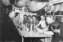 Le Chef d’état-major de la marine, le Vice-amiral Rollo Mainguy, prend le café avec des matelots de l’Athabaskan pendant sa visite à bord, en février 1953, dans les eaux coréennes.