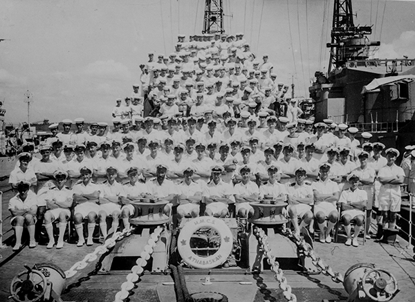 A large group of sailors poses for a photo on the deck of a ship.