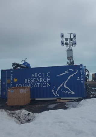 The iTel pole‑mounted unit sits in front of a shipping container that bears the Arctic Research Foundation logo.