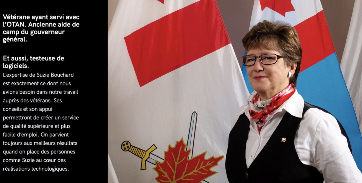 A photograph of Suzie, a veteran, standing in front of Canadian military flags. Version textuelle ci-dessous: