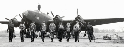 Nine Canadian airmen walk towards a plane with their gear