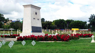 Monument commémoratif au centre d’un parterre de fleurs rouges et de gazon vert