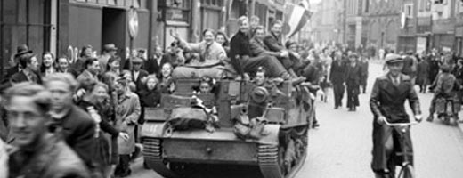 Soldiers riding on a tank through town on a crowded street with people celebrating the end of the war