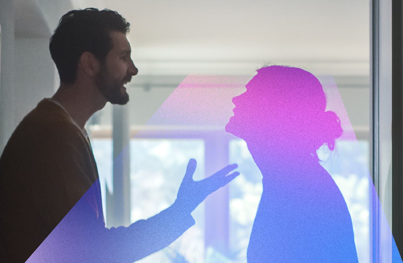 A man and woman facing each other indoors, with the man speaking and gesturing with an open hand, while the woman stands with her head tilted back, silhouetted against a bright window.