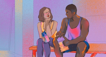 Un homme et une femme, assis sur un banc, sourient et discutent en tenant tous deux des bouteilles d’eau.