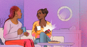 Two friends sitting on a couch holding mugs